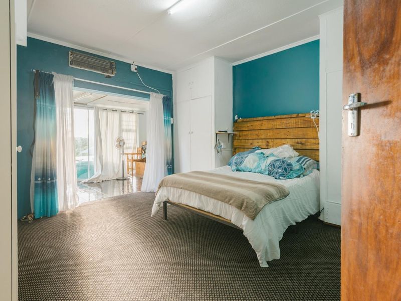 Spacious bedroom featuring built-in cupboards, air conditioning, and direct access to an adjoining sunroom through sliding glass doors.
