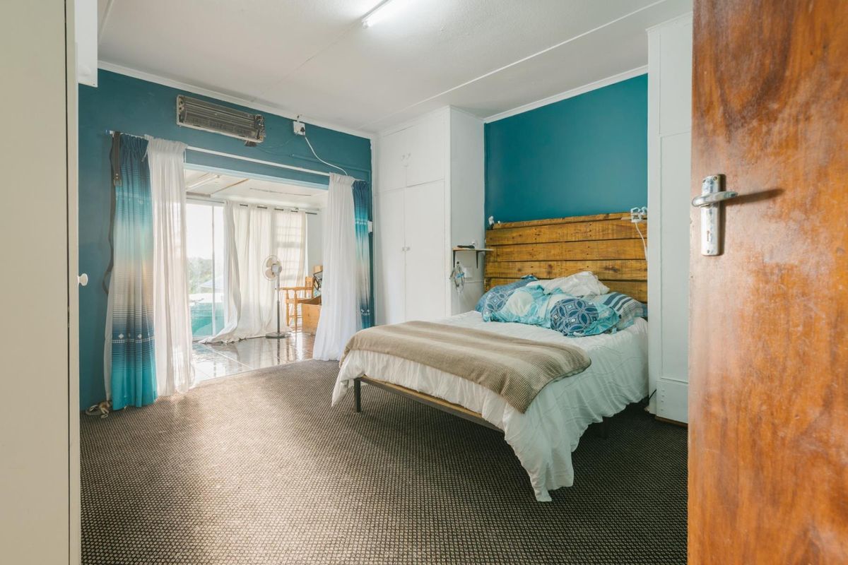 Spacious bedroom featuring built-in cupboards, air conditioning, and direct access to an adjoining sunroom through sliding glass doors.
