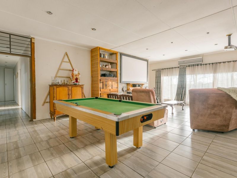 Spacious living area featuring tiled flooring, recessed lighting, and a wall-mounted projector screen, offering a versatile space for entertainment and relaxation.