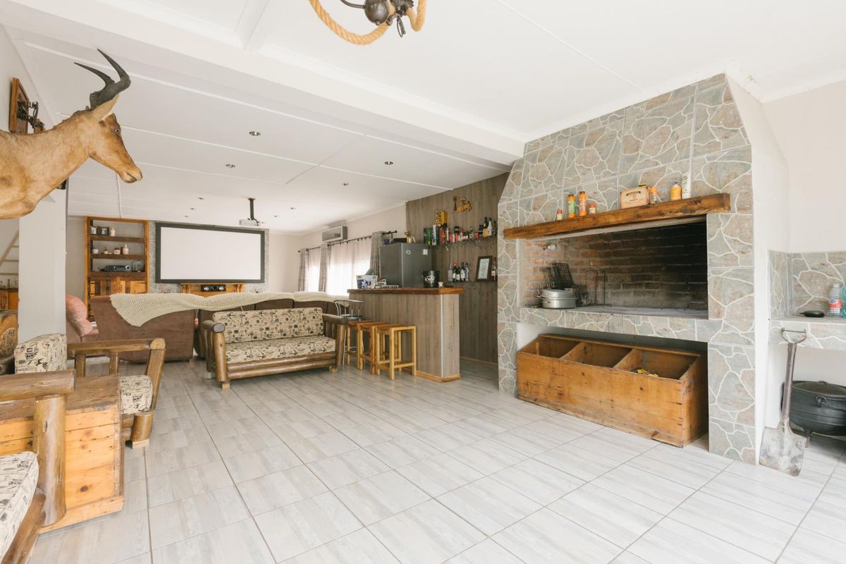 Spacious living area featuring a large built-in stone fireplace, integrated bar counter, and tiled flooring, suitable for entertainment and relaxation.