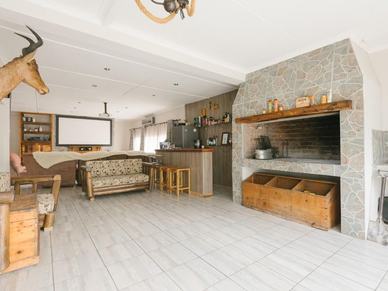 Spacious living area featuring a large built-in stone fireplace, integrated bar counter, and tiled flooring, suitable for entertainment and relaxation.