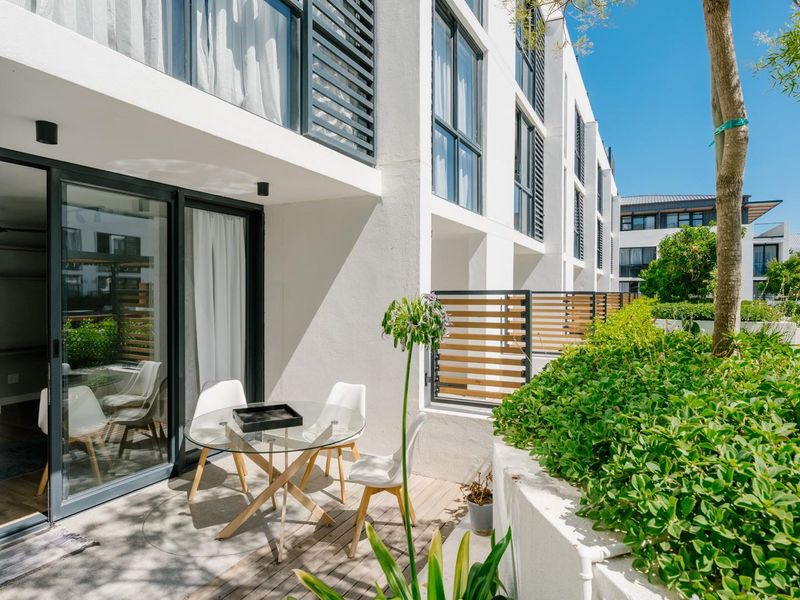 A modern ground-floor patio featuring timber decking, sliding glass doors, and a private landscaped garden area.
