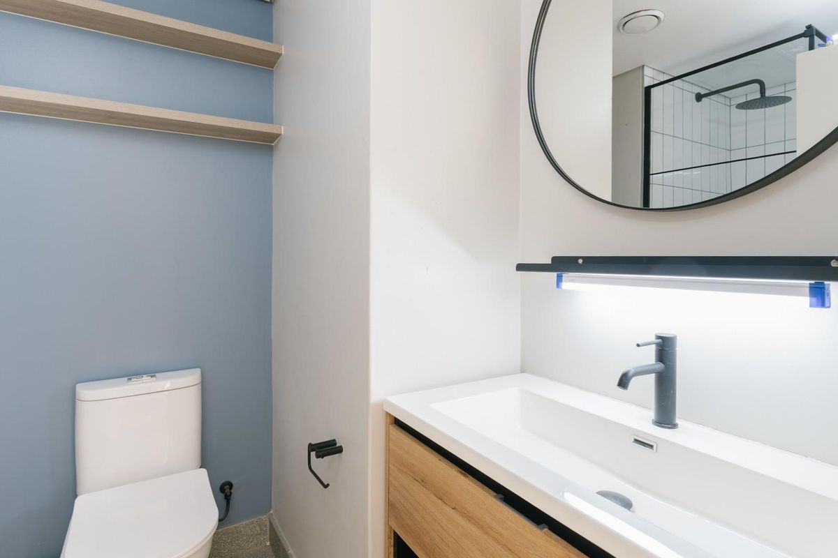 Modern bathroom featuring a sleek vanity with integrated basin, floating shelves, contemporary matte black fixtures, and a separate shower enclosure.