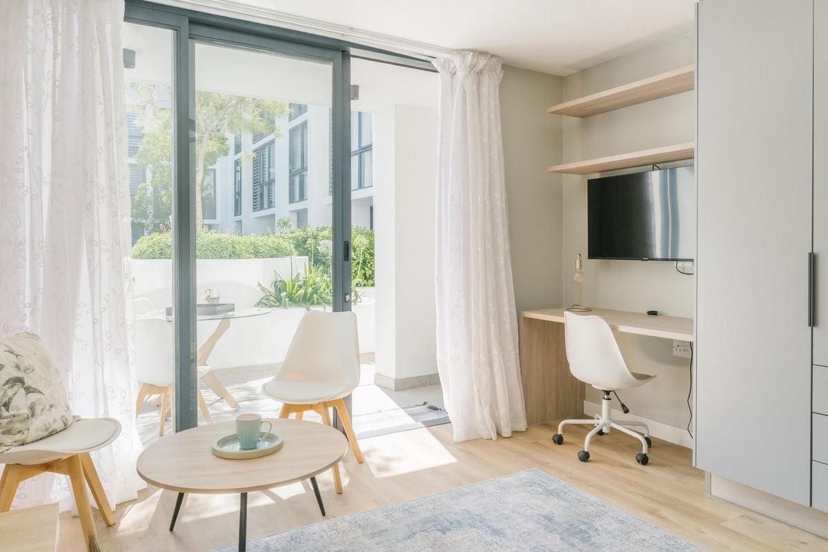 Bright living area featuring a built-in desk, floating shelves, and large sliding glass doors that open onto a private patio.
