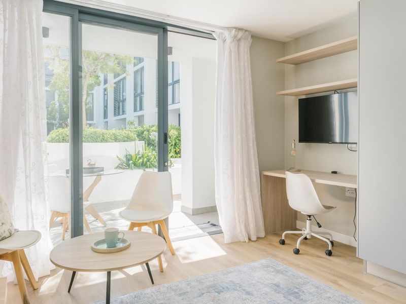 Bright living area featuring a built-in desk, floating shelves, and large sliding glass doors that open onto a private patio.