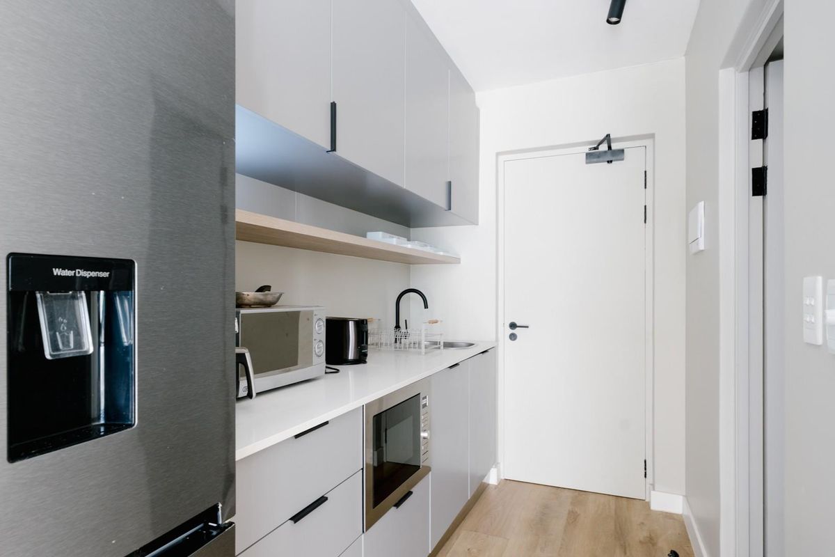 Modern galley-style kitchen featuring sleek grey cabinetry, stone countertops, integrated microwave, and high-quality finishes throughout.