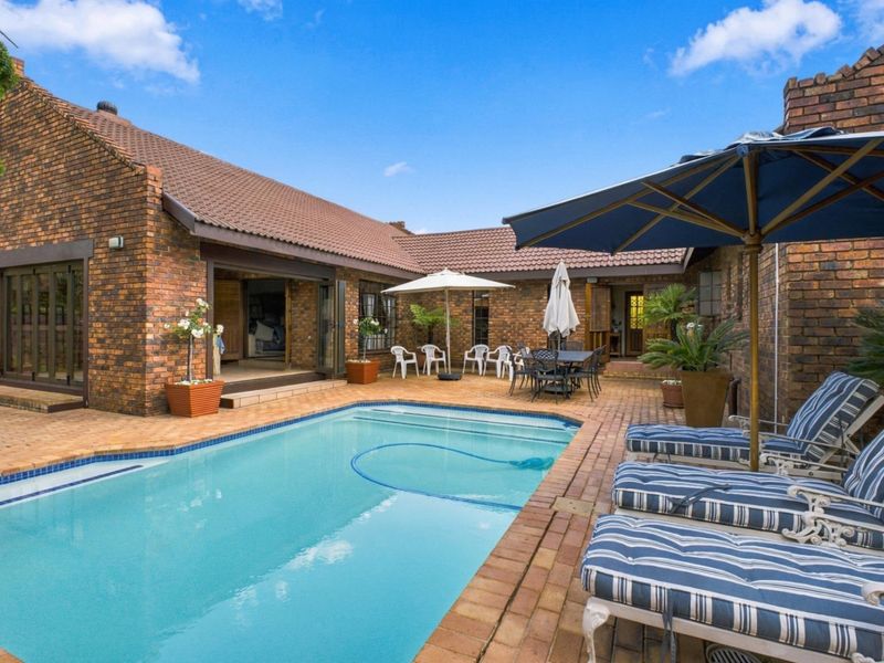 A well-maintained outdoor pool area featuring a swimming pool, brick paving, and direct access to the home through sliding doors.