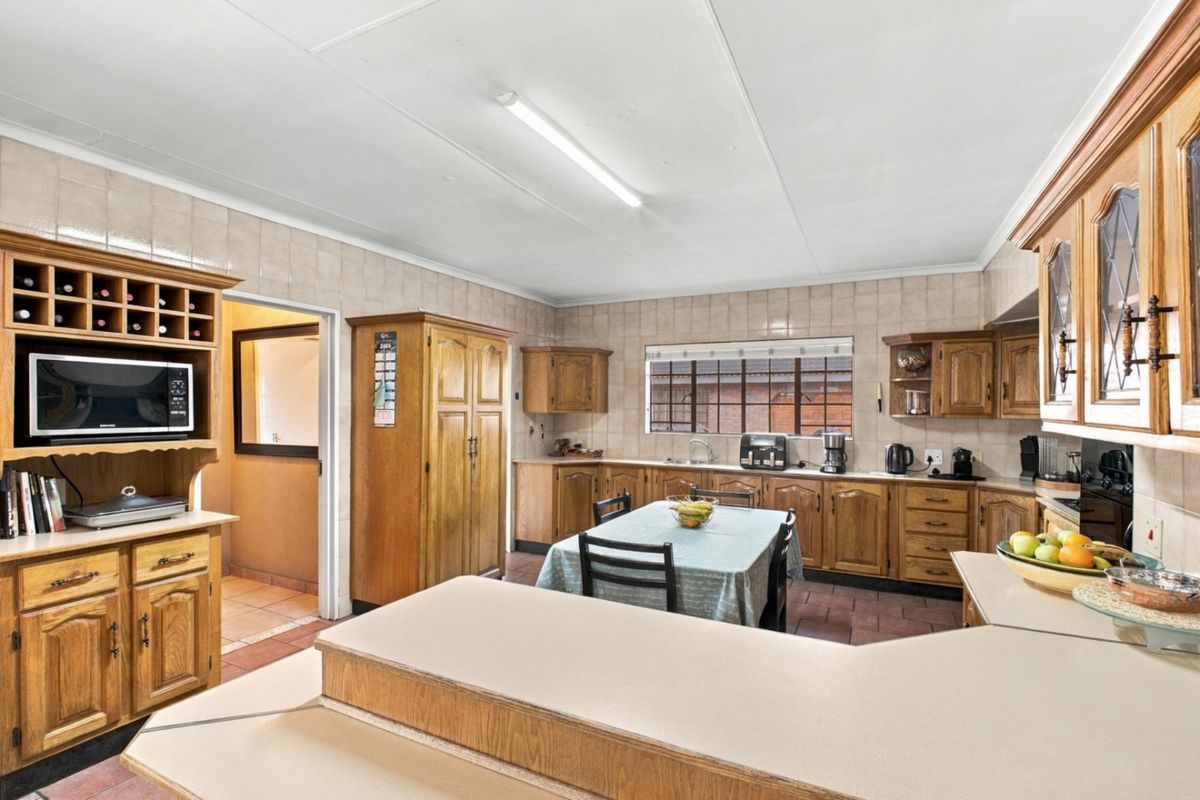 A spacious kitchen featuring extensive wooden cabinetry, laminate countertops, tiled backsplash, and a functional layout with a built-in wine rack.