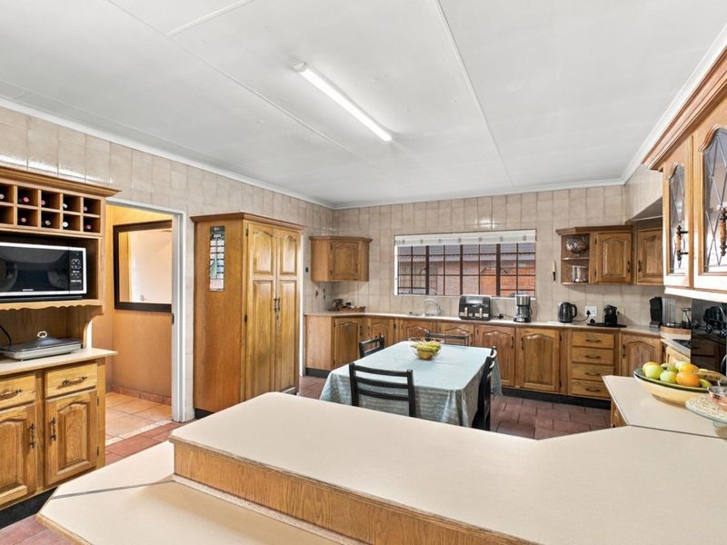 A spacious kitchen featuring extensive wooden cabinetry, laminate countertops, tiled backsplash, and a functional layout with a built-in wine rack.