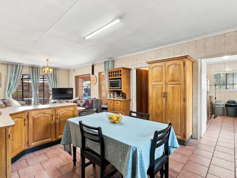 Open plan kitchen and dining area featuring tiled flooring, built-in wooden cabinetry, and a central island, offering a functional layout with direct access to adjacent rooms.