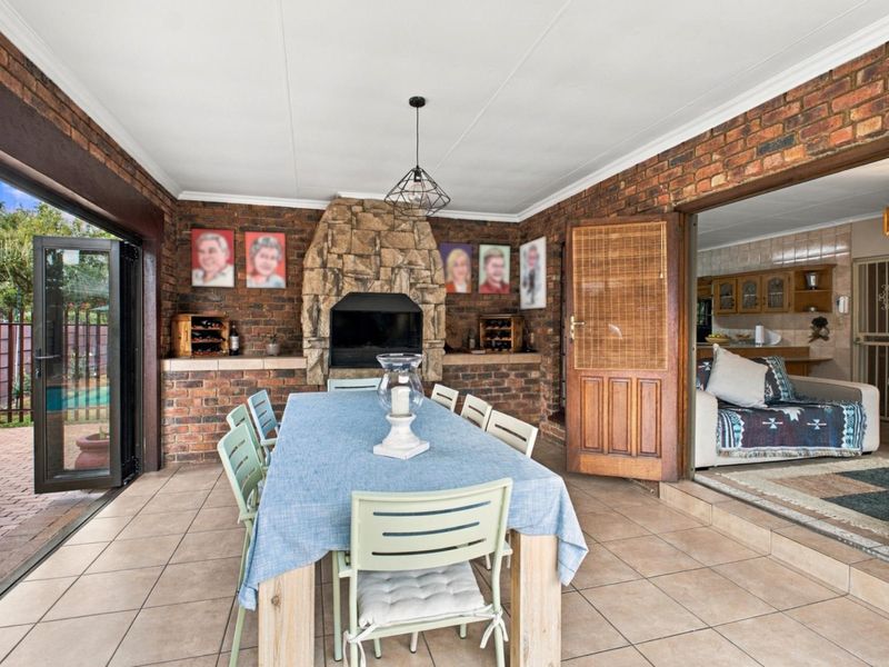Covered patio area featuring exposed brick walls, a built-in stone fireplace, and tiled flooring, providing a seamless transition to the indoor living space.