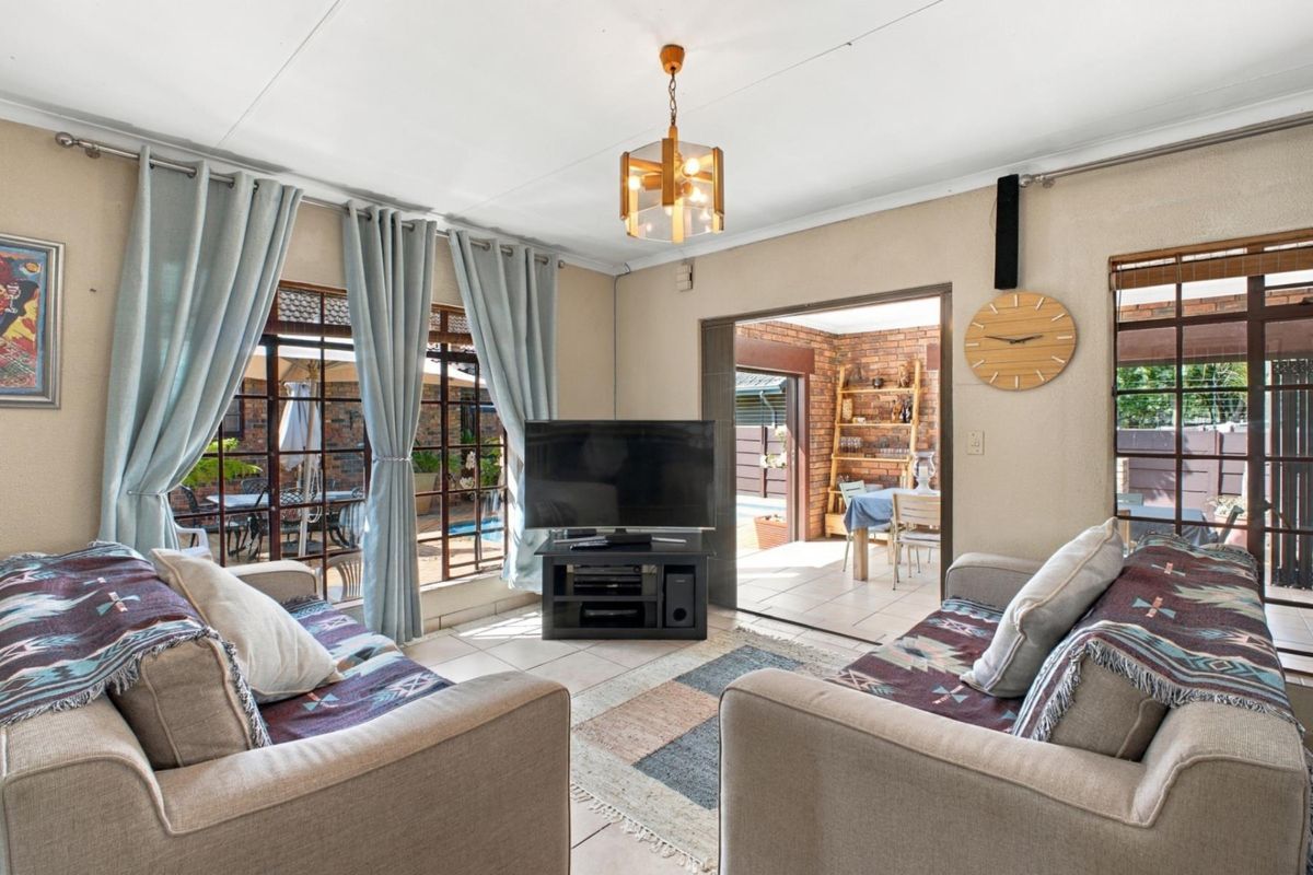 A comfortable living room featuring tiled flooring and large sliding glass doors that provide natural light and access to an adjacent patio area.