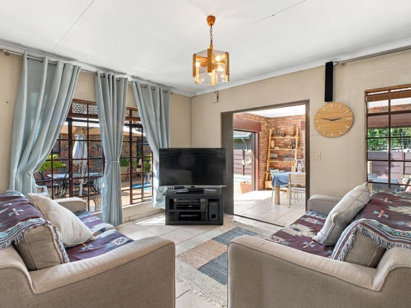 A comfortable living room featuring tiled flooring and large sliding glass doors that provide natural light and access to an adjacent patio area.