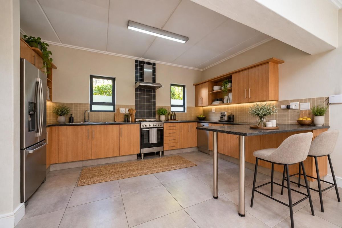 Modern kitchen featuring light wood cabinetry, granite countertops, tiled backsplash, integrated lighting, and a functional breakfast bar area with tiled flooring.