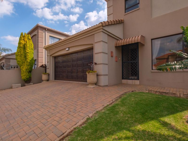 Front elevation of a townhouse featuring a paved driveway, double garage, and a secure entrance with an awning.