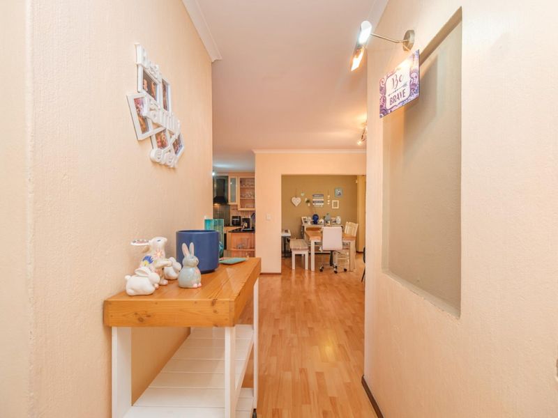 A bright hallway featuring laminate flooring and a wall-mounted light fixture, providing a clear transition into the open-plan living and dining area.