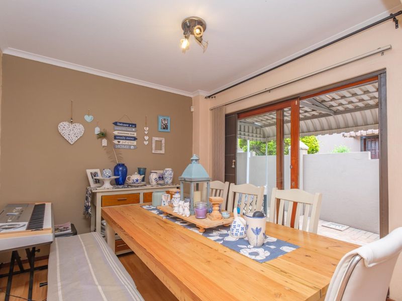 A dining room featuring laminate flooring, a ceiling light fixture, and a sliding glass door providing access to the outdoor patio area.