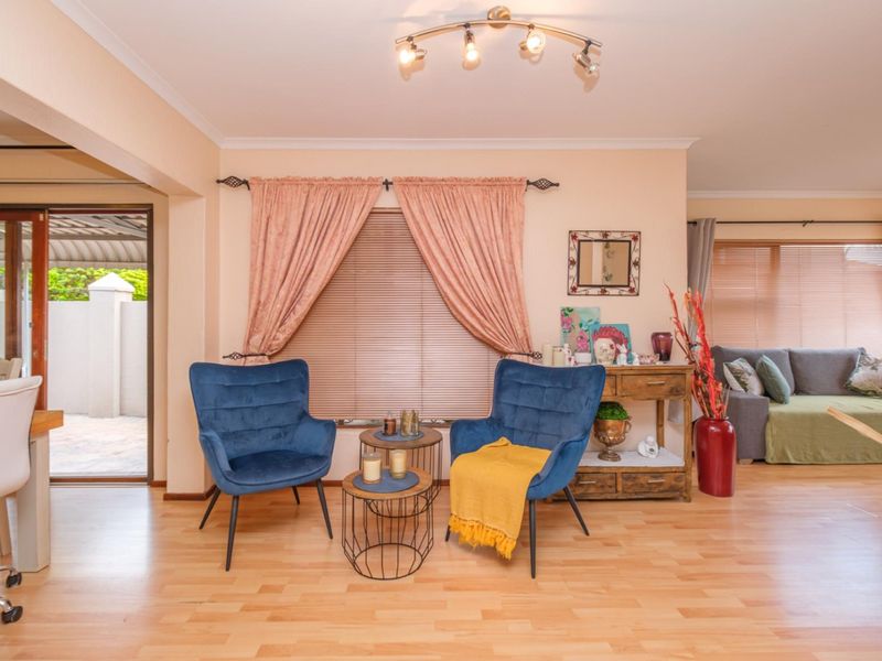 Bright open-plan living area featuring laminate flooring, track lighting, and a sliding glass door providing seamless access to the outdoor patio space.