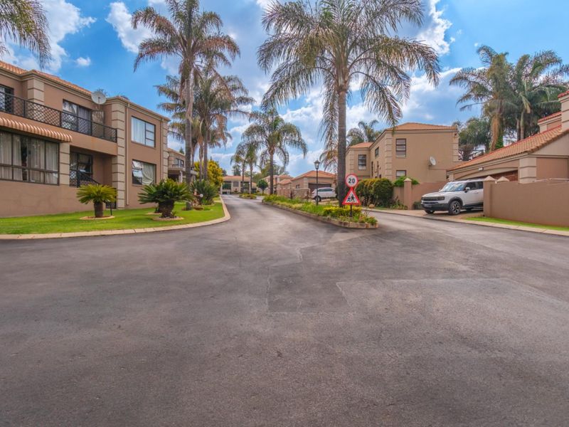 A view of the paved internal driveway and surrounding townhouse units within a well-maintained residential complex.