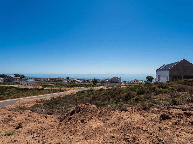 An elevated view overlooking a coastal residential area with a clear horizon and ocean backdrop.