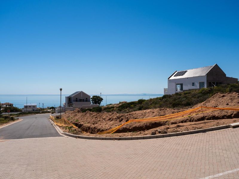A view of a vacant residential plot featuring paved road access and ongoing site excavation, situated in a coastal neighborhood.