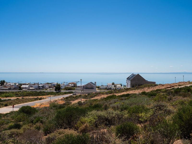 A scenic elevated view overlooking the coastal landscape, nearby residential properties, and the ocean horizon.