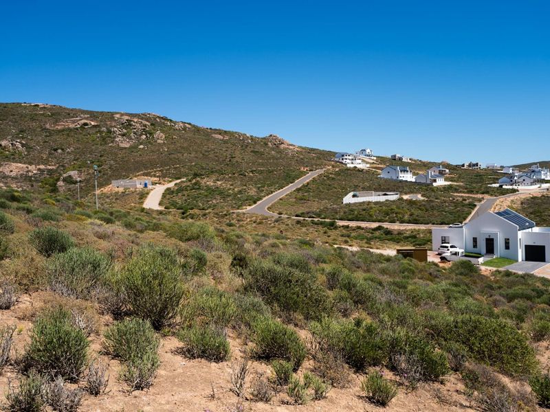 An elevated aerial view of a residential development area featuring paved roads and surrounding natural landscape.