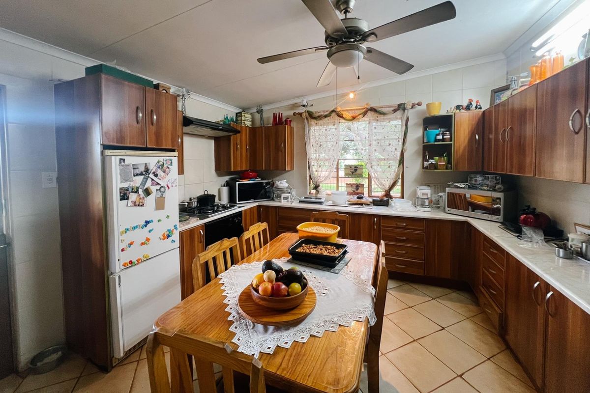 A functional kitchen featuring wooden cabinetry, laminate countertops, a built-in oven, and tiled flooring, offering a traditional farm-style aesthetic.