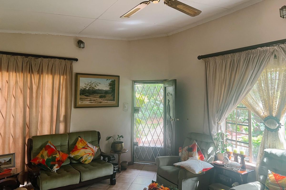 A cozy living room featuring tiled flooring, a ceiling fan, and a secure entrance door with a metal security gate.