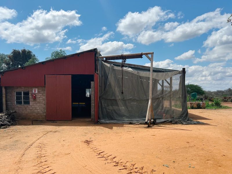 A functional farm utility shed featuring brick and corrugated metal construction with an integrated overhead hoist system for agricultural operations.