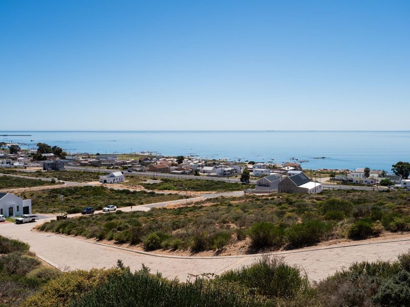 Elevated view overlooking the coastal residential area and the ocean, showcasing the surrounding landscape and local infrastructure.