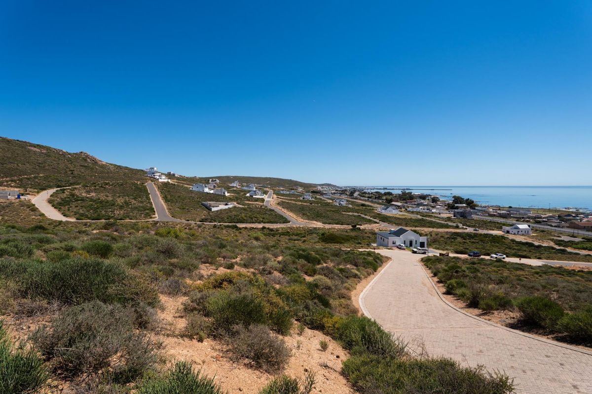 An elevated aerial view of a residential development site featuring paved roads and coastal landscape views.