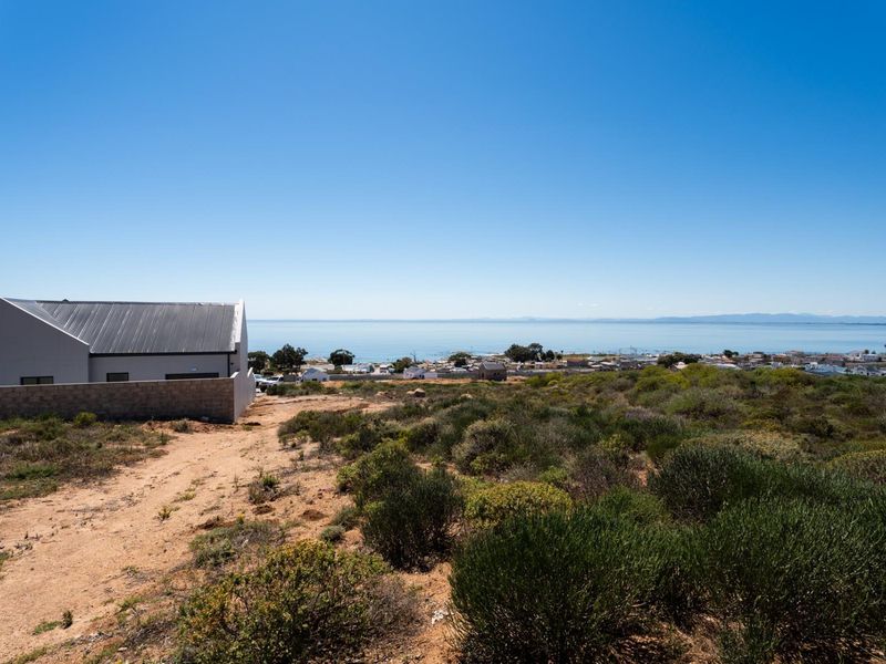 A scenic view overlooking the coastal landscape and nearby residential area from the vacant residential plot.
