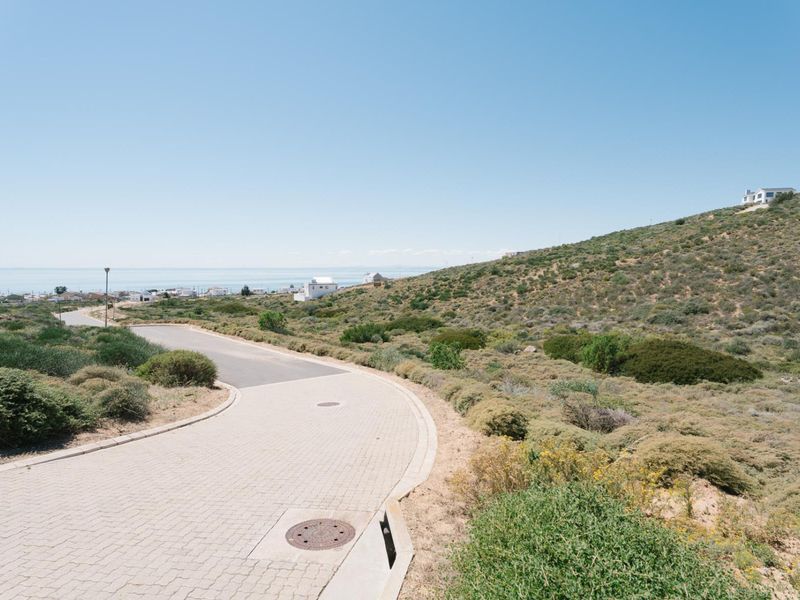 A view of the paved residential street and surrounding coastal landscape, featuring established infrastructure and clear access to the property.
