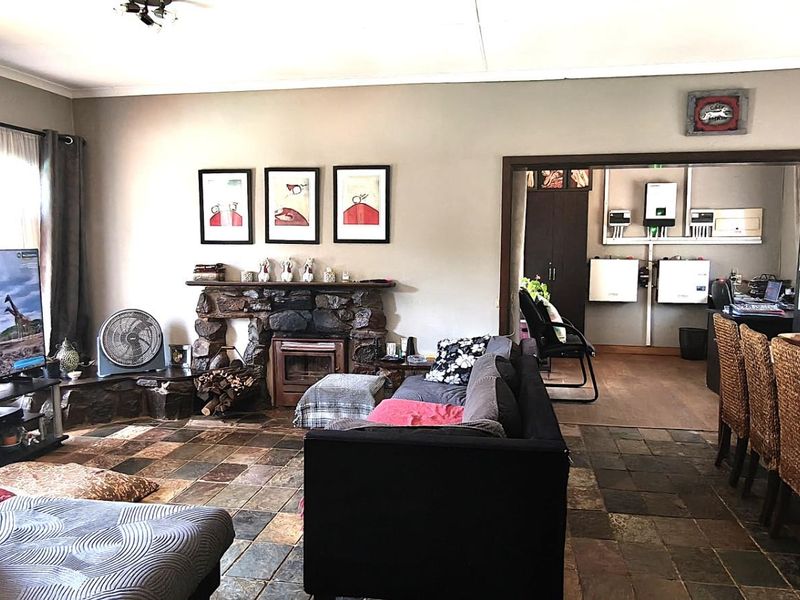 Spacious open-plan living and dining area featuring rustic stone fireplace, slate tile flooring, and integrated solar power infrastructure in the adjacent room.