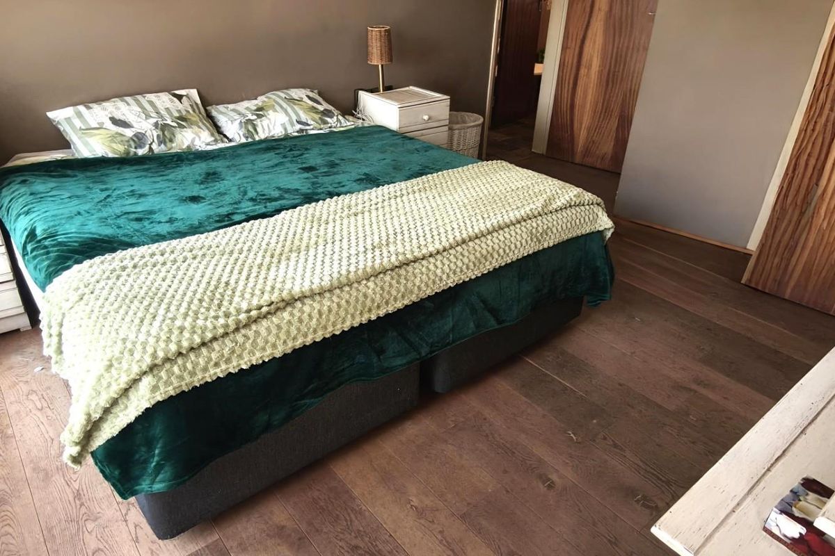 A bedroom featuring timber flooring, a built-in wardrobe, and a solid wood door, offering a functional and comfortable living space.