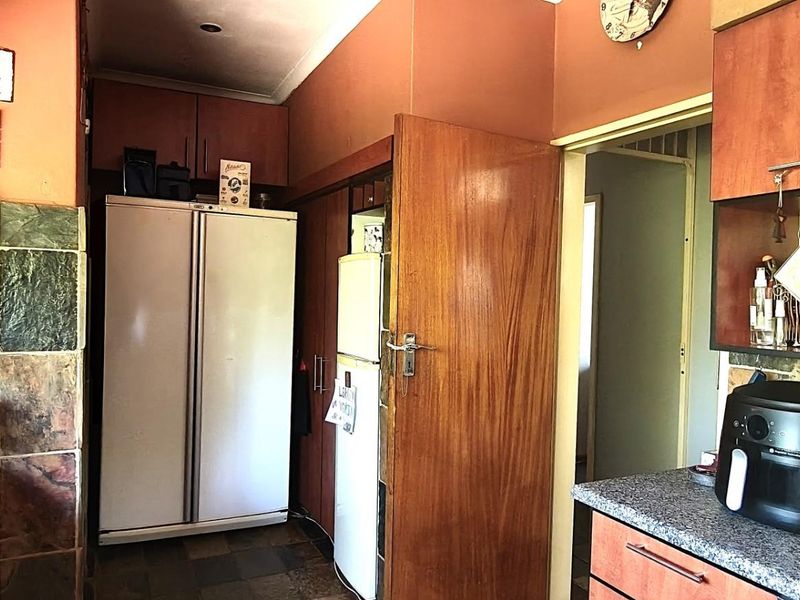 A functional kitchen featuring built-in cabinetry, stone-look wall tiles, and laminate countertops, offering a practical layout with integrated storage solutions.