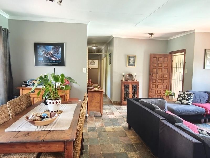 Spacious open-plan living and dining area featuring natural slate tile flooring and a classic timber panelled entrance door.