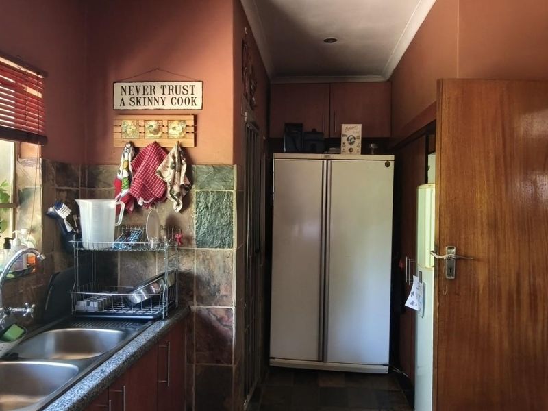 A functional kitchen featuring a double basin sink, stone-look tiled splashback, and built-in cabinetry with ample storage space.