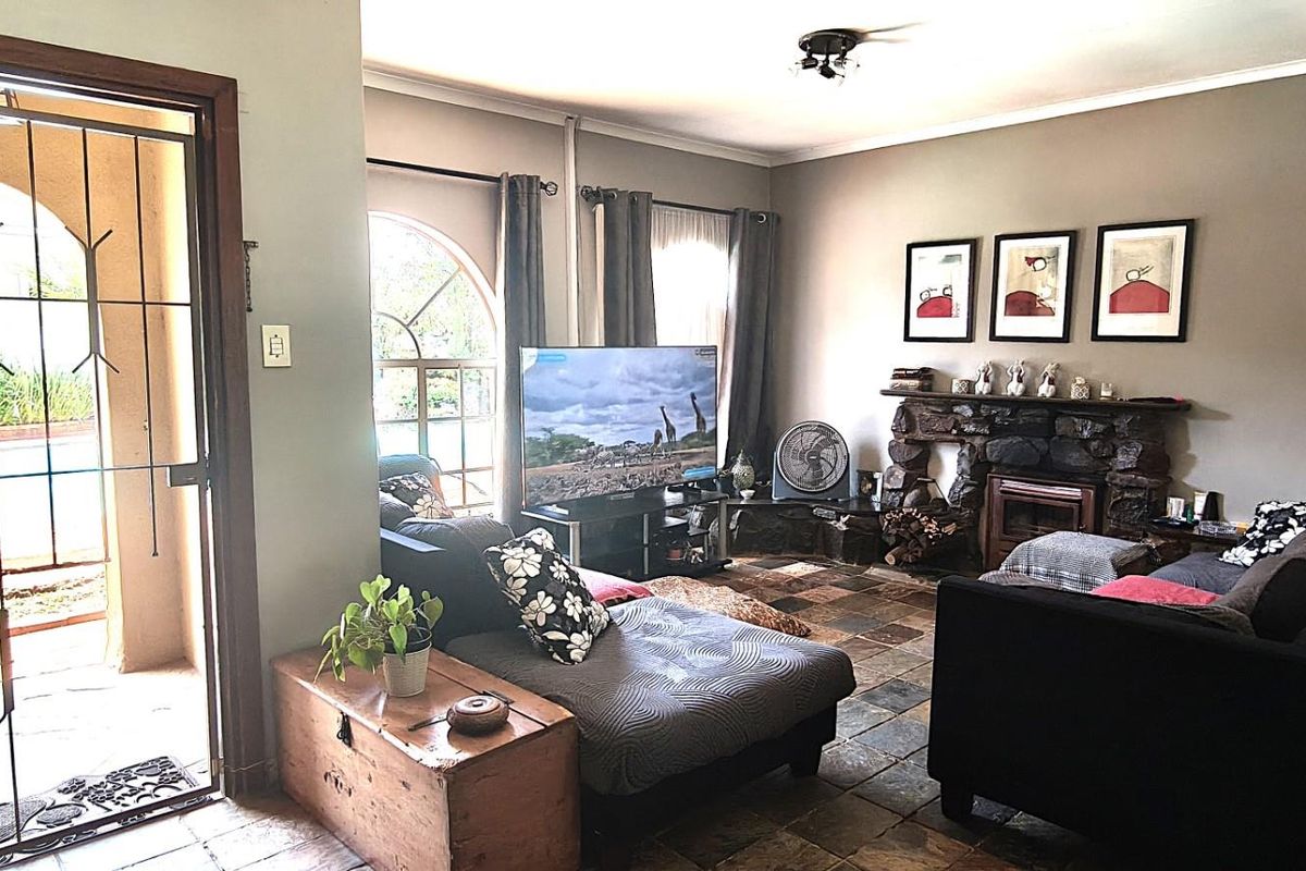 Spacious living room featuring rustic slate tile flooring, a prominent stone fireplace, and an arched window providing natural light.