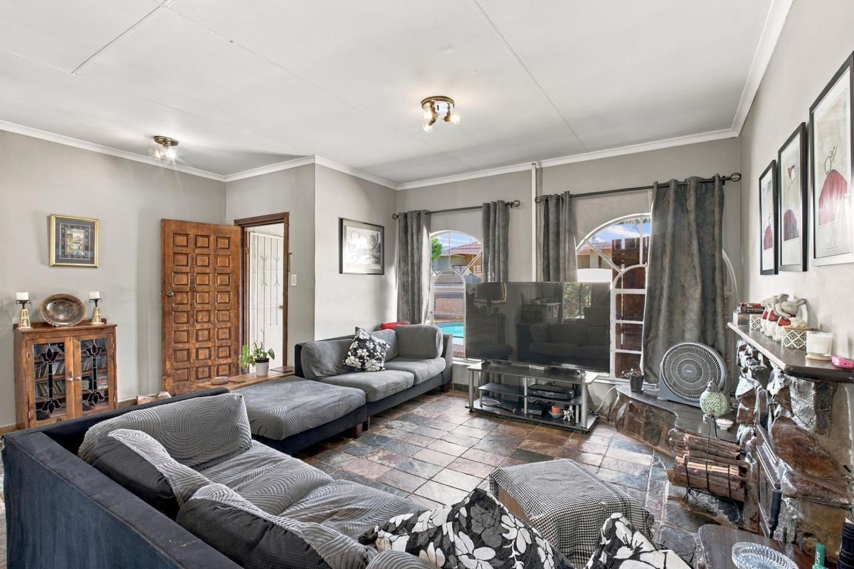 A living room featuring a stone fireplace, tiled flooring, and arched windows that provide natural light and a view of the outdoor area.
