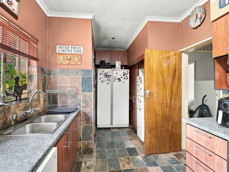 A functional kitchen featuring granite countertops, double bowl stainless steel sink, and slate tile flooring with ample built-in cabinetry.