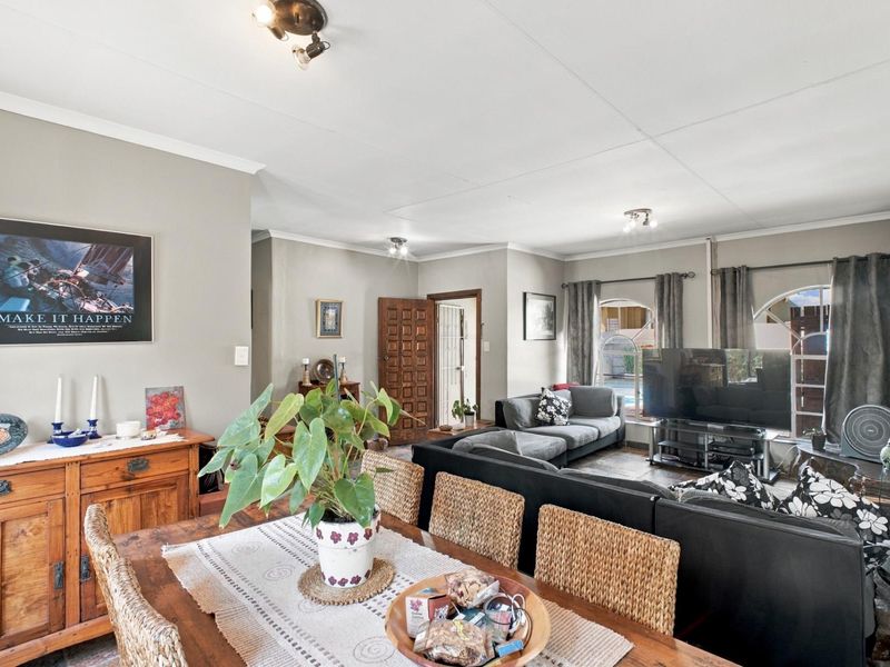 Spacious open-plan living and dining area featuring tiled flooring, ceiling spotlights, and distinctive arched windows overlooking the exterior.