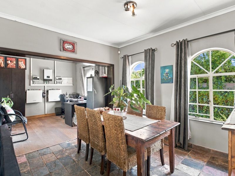 Open plan dining area featuring slate tile flooring and arched windows, with an adjacent office space equipped with a solar inverter system.