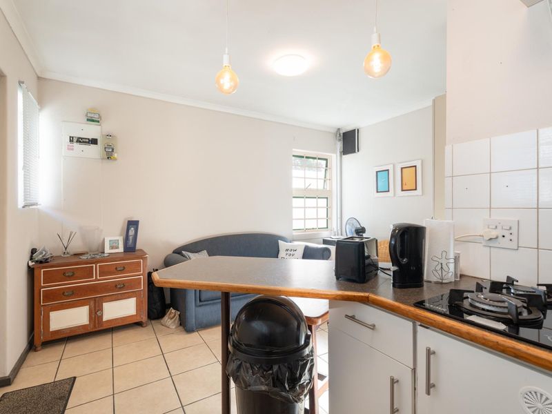 Open-plan kitchen and living area featuring tiled flooring, built-in cabinetry with a gas hob, and pendant lighting.
