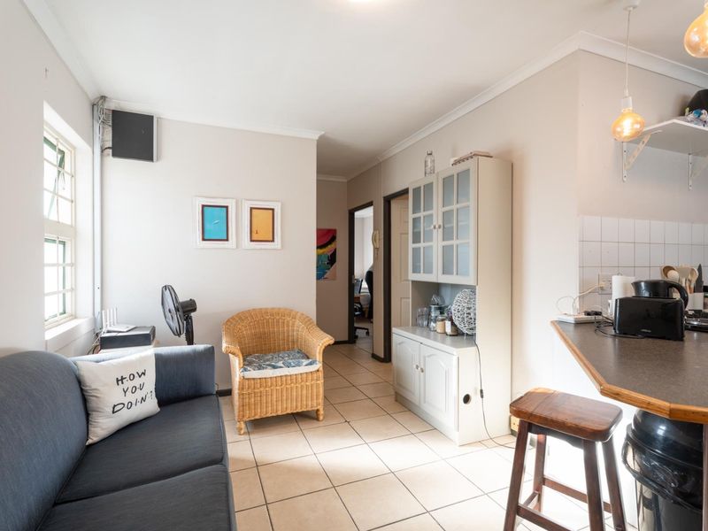 Open plan living area featuring tiled flooring, a kitchen breakfast bar, and neutral wall finishes, creating a functional and connected living space.