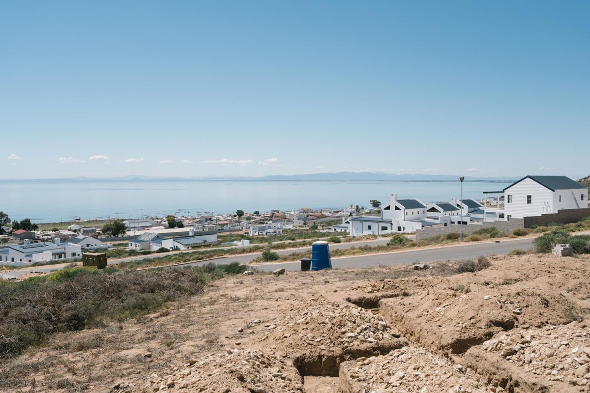 A scenic elevated view overlooking a coastal residential neighborhood and the ocean, showcasing the surrounding landscape and local development.