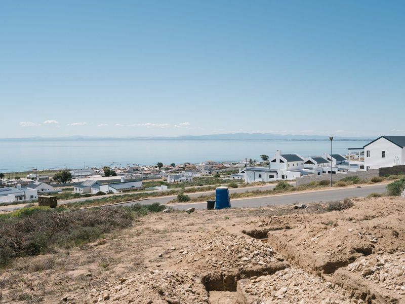 A scenic elevated view overlooking a coastal residential neighborhood and the ocean, showcasing the surrounding landscape and local development.