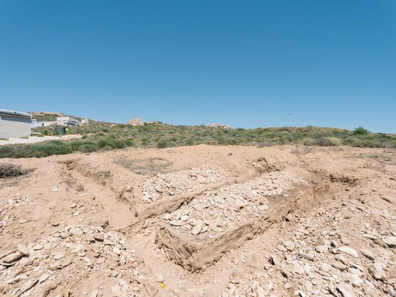 A vacant residential plot featuring excavated foundation trenches in rocky soil, ready for further development.