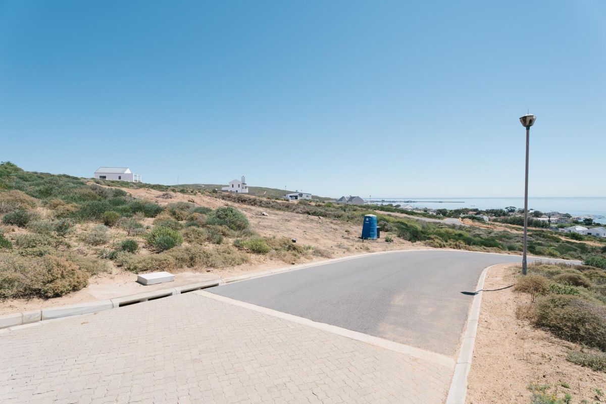 A view of the paved street and infrastructure bordering the vacant residential land, featuring coastal landscape views in the distance.